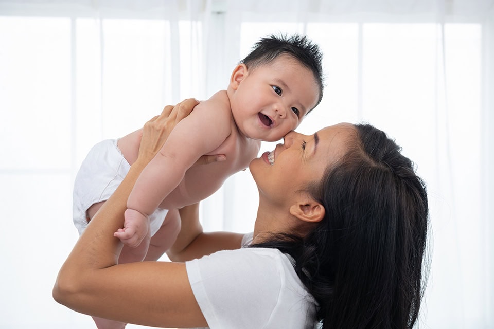 960 laughing mother lifting her adorable newborn baby son air