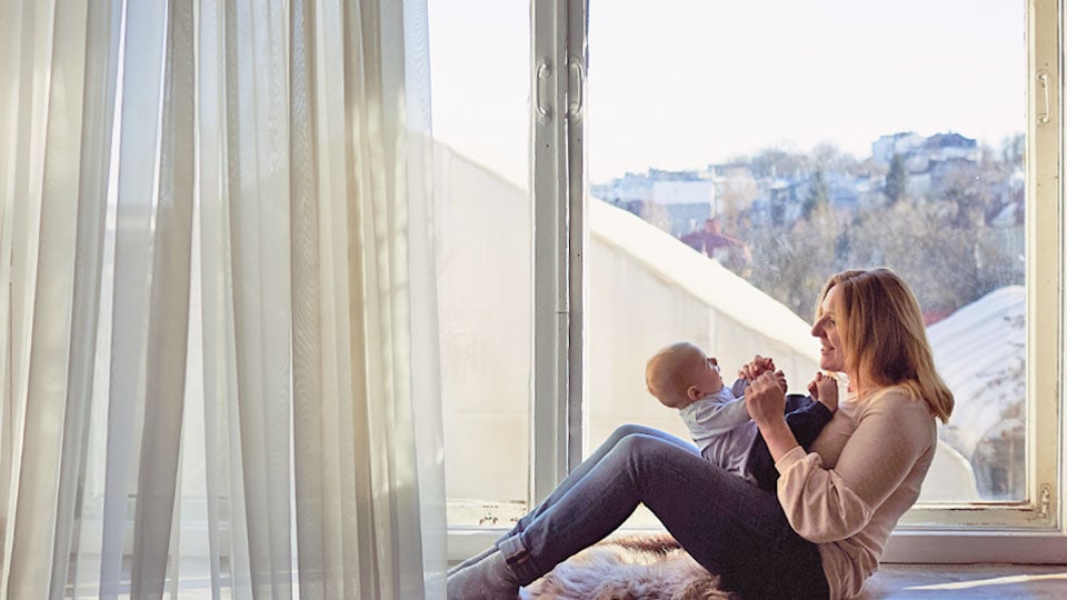 mother embraces her son sits by window 2